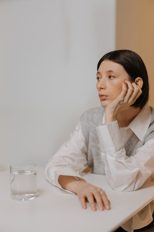 Woman in White Dress Shirt Sitting Behind a Table