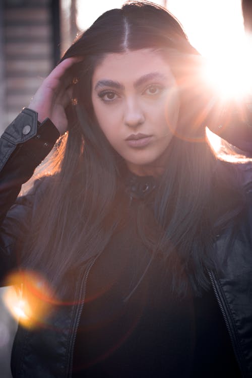 Photo of a Woman in a Black Leather Jacket Touching Her Hair