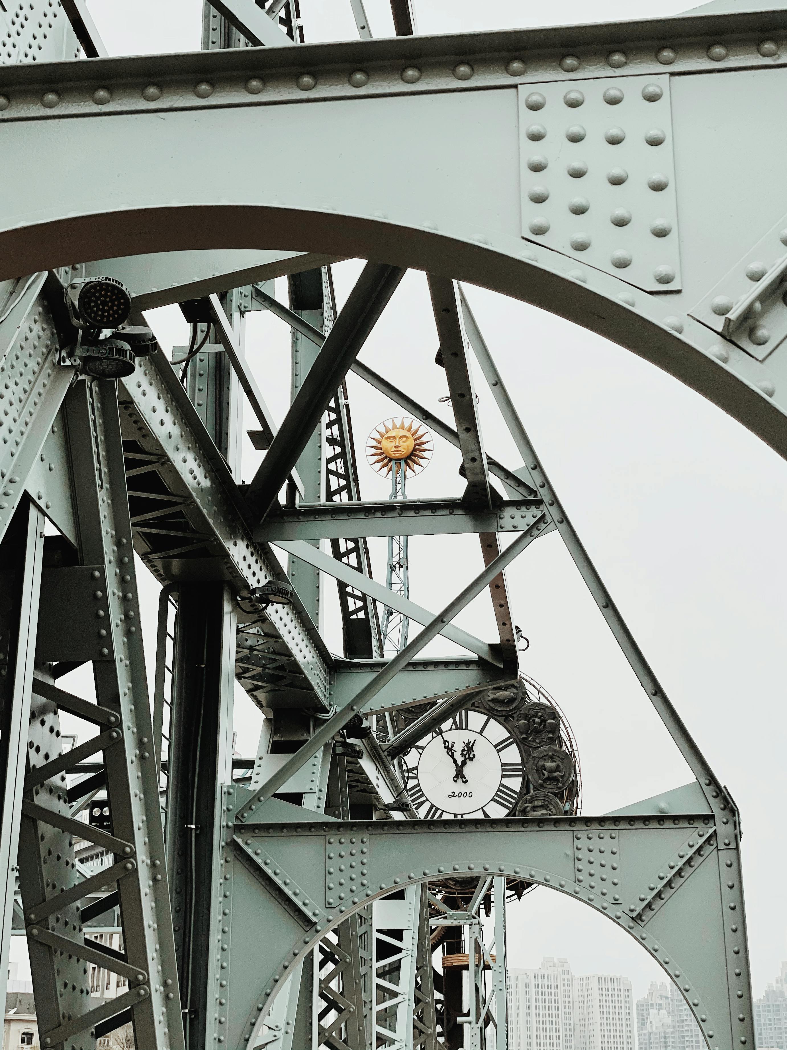 Close-up of a steel truss bridge structure featuring a prominently visible clock tower in Tianjin, China.