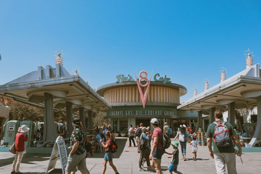 A lively scene at a retro-themed cafe entrance with tourists exploring the area on a sunny day.
