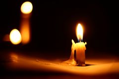 Close-up of a burning candle against a dark background with dripping wax.