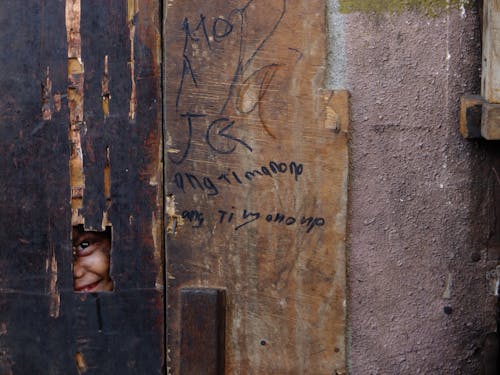 Free Smiling Kid Peeking through the Plywood Stock Photo