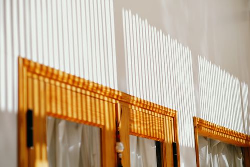 Free Bright sunlight casts striped shadows on a room's wall, creating a warm indoor ambiance. Stock Photo