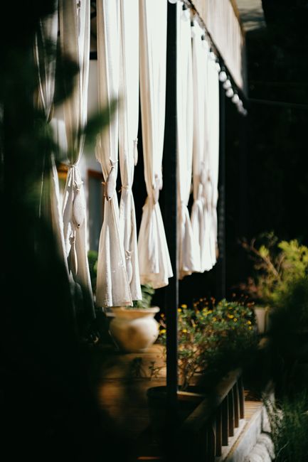 Elegantly draped outdoor curtains with soft lighting and garden views create a tranquil nighttime ambiance.