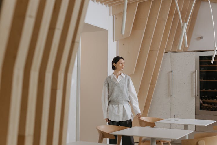 Woman Standing By Desks In Wood Covered Room