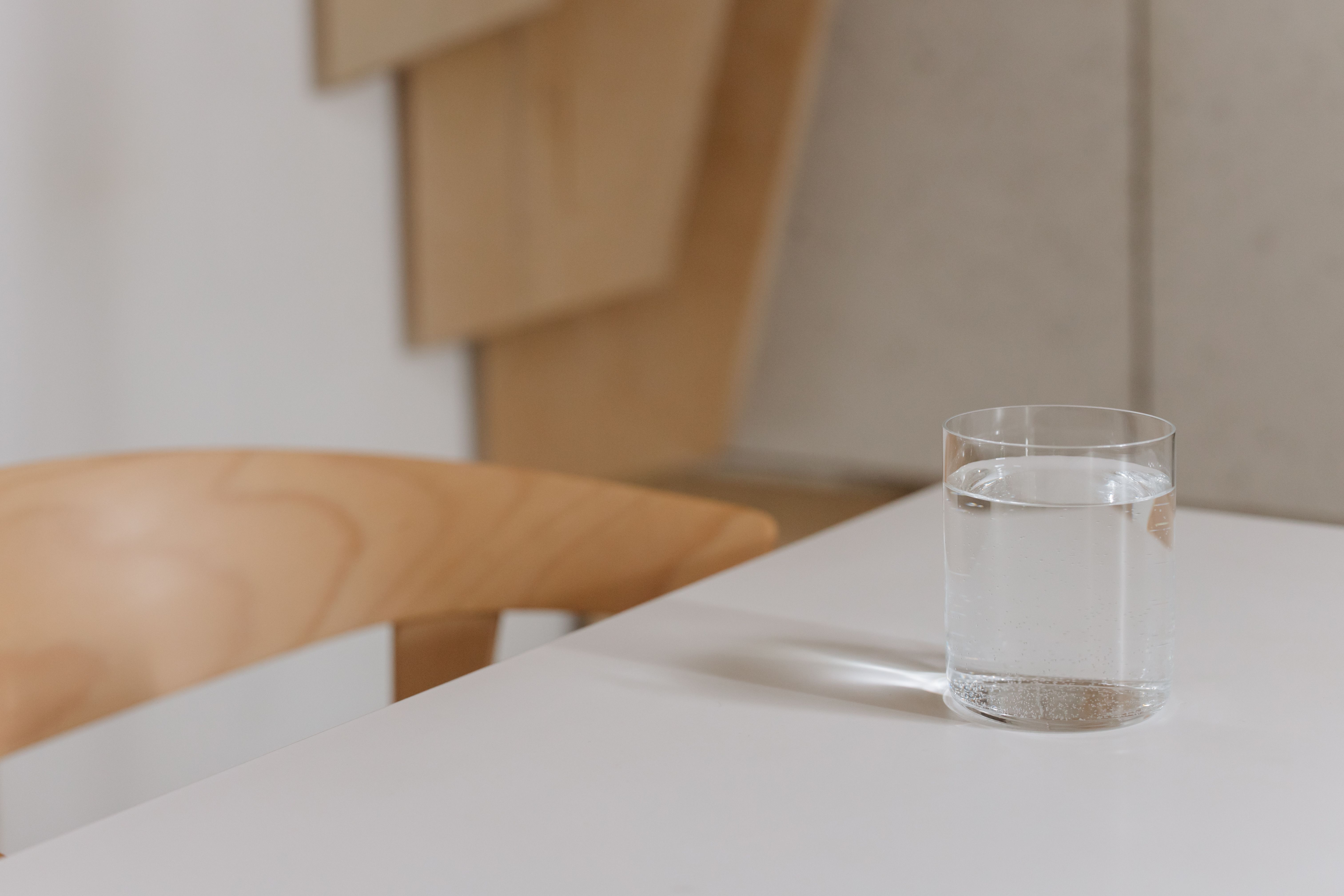 Simple and elegant composition of a water glass on a modern wooden table indoors.
