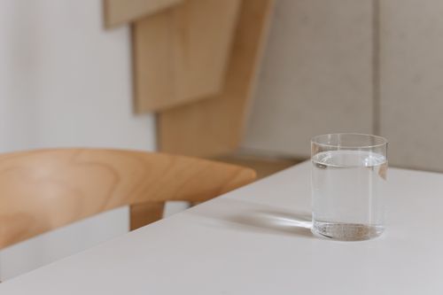 Free Simple and elegant composition of a water glass on a modern wooden table indoors. Stock Photo