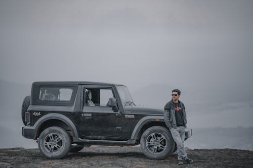 Man in Black Jacket Standing Beside Black SUV