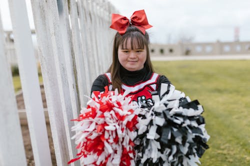 Woman in Cheerleader Outfit Standing beside Wooden Fence