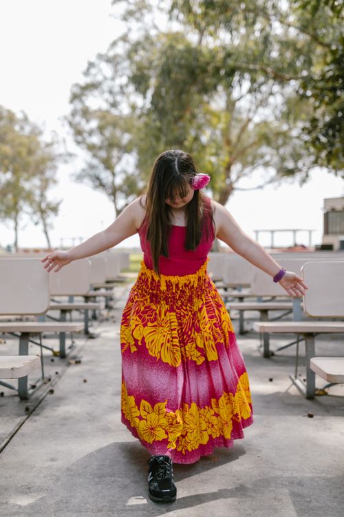 Free Young woman in colorful dress dancing outdoors in a park with benches and trees. Stock Photo