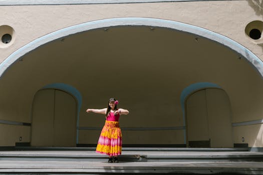 A young woman in a vibrant floral dress poses confidently on a stage, showcasing elegance and style.