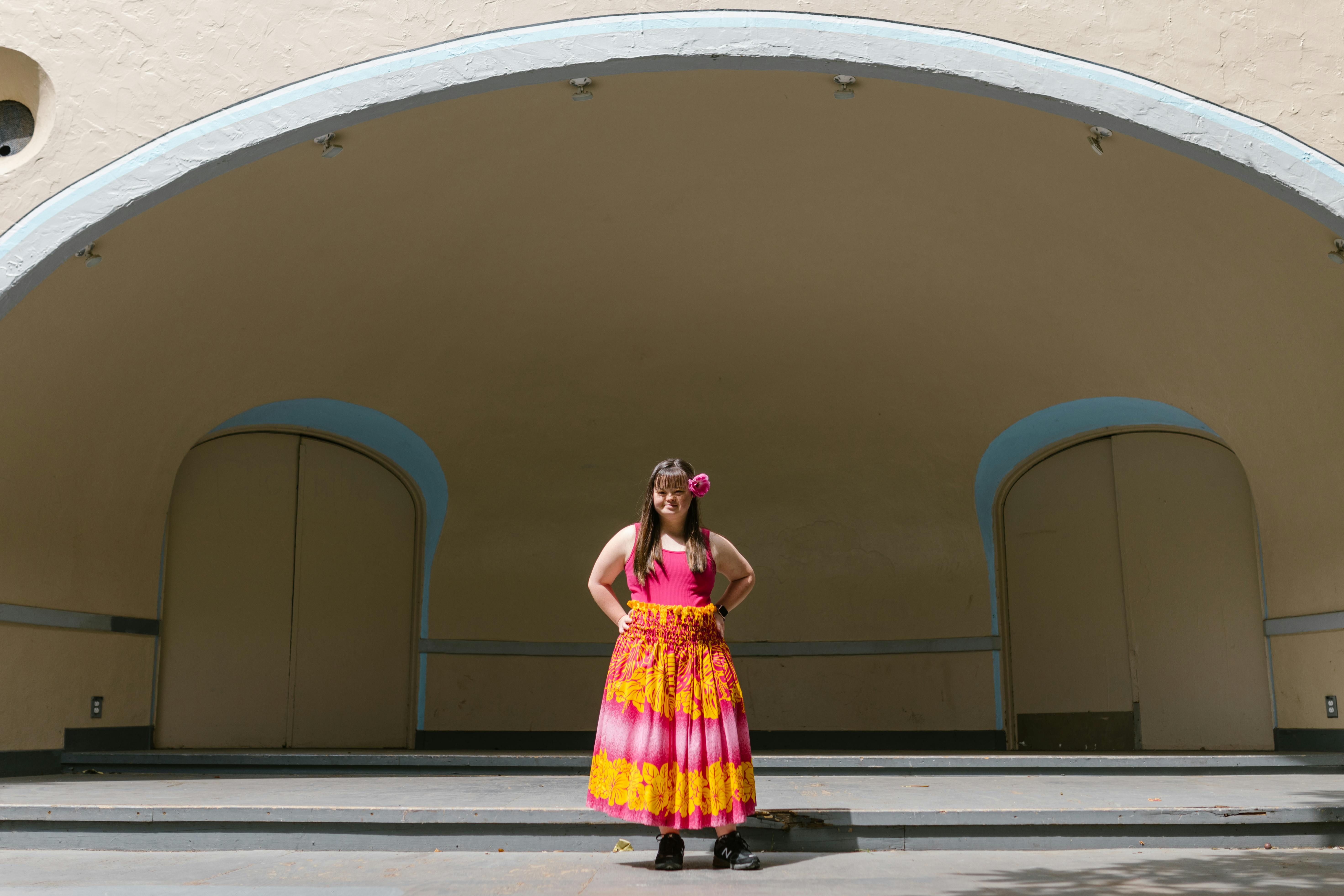 Free Young woman with Down syndrome posing confidently on stage in a vibrant dress. Stock Photo