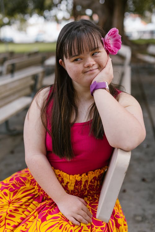 A Girl with a Flower on Her Ear Sitting on a Bench