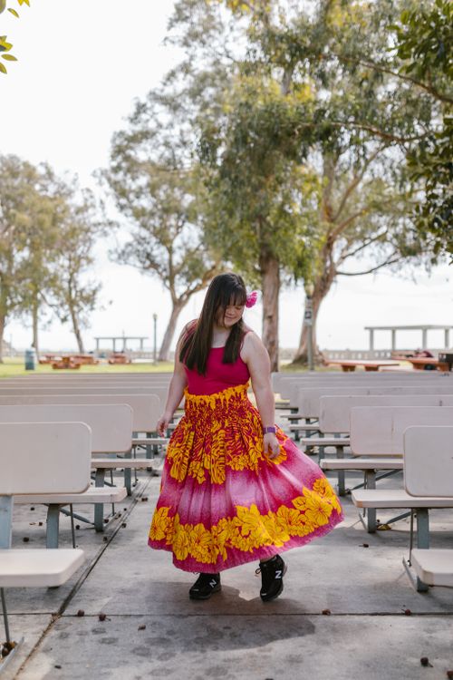 Free Woman in a colorful dress enjoying a dance outdoors on a sunny day among trees and benches. Stock Photo