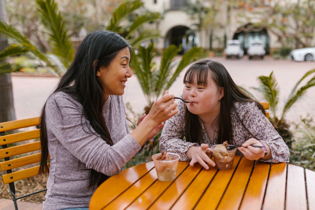 A caregiver and a young woman with Down syndrome sharing a joyful moment together