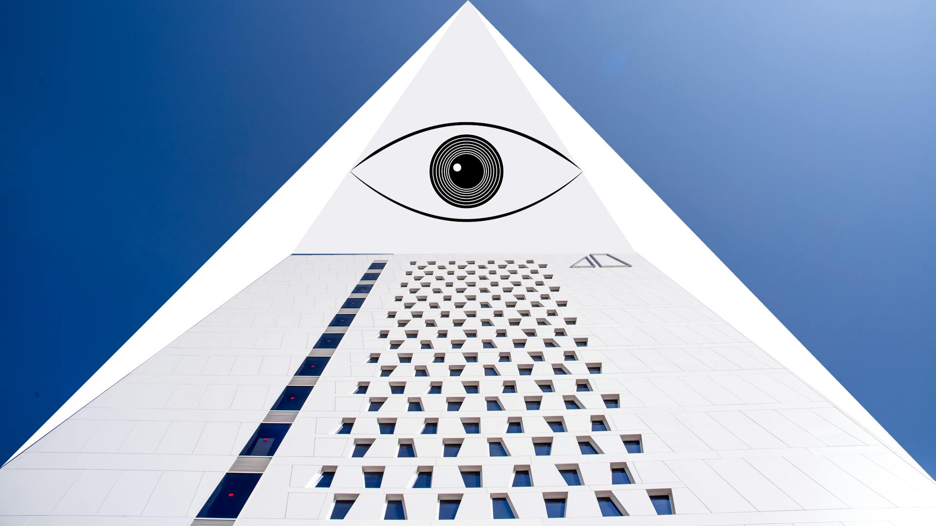 Modern building with geometric shapes and eye symbol under a clear blue sky.