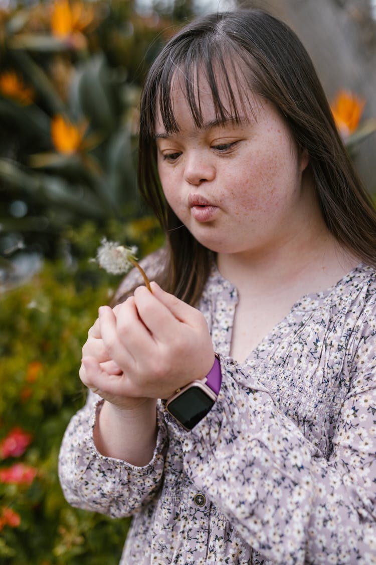 Woman In Floral Top Blowing A Dandelion Flower