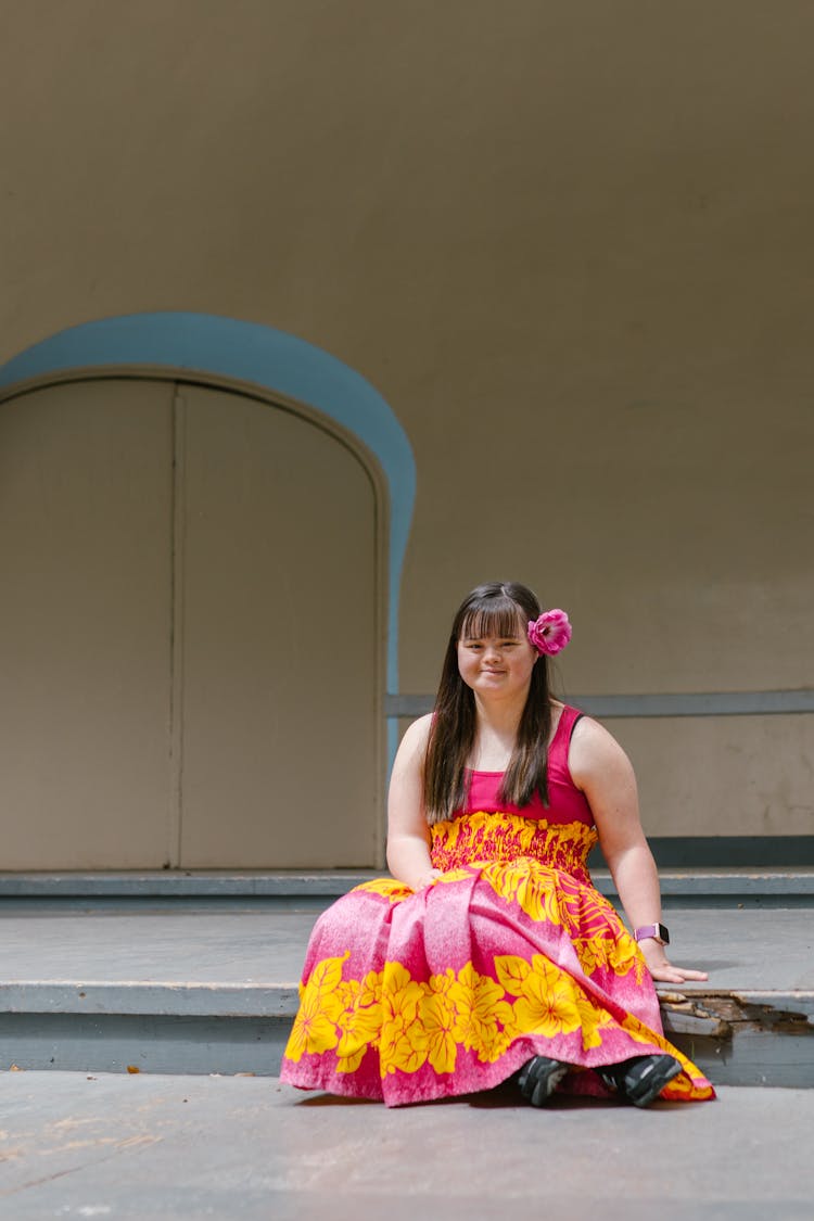 A Girl With A Flower On Her Ear Sitting On A Stage