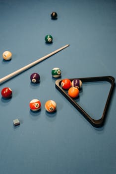 Vibrant billiard balls and cue on a pool table with chalk and rack.