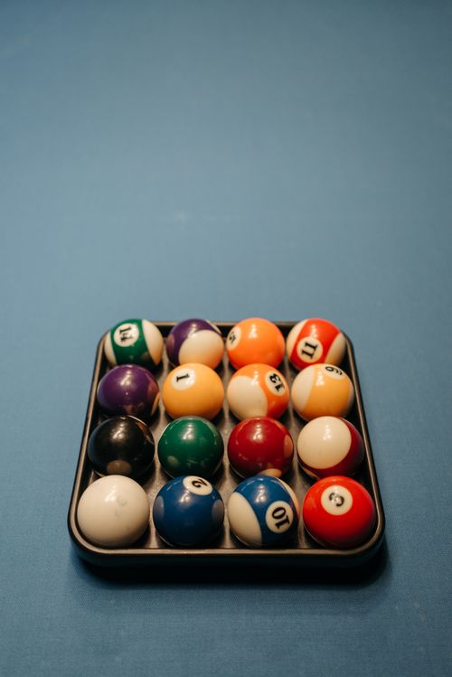 Free Vividly colored billiard balls neatly arranged on a blue felt pool table ready for play. Stock Photo
