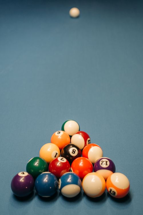 Free Colorful pool balls arranged on a billiard table with a cue ball in the distance. Stock Photo