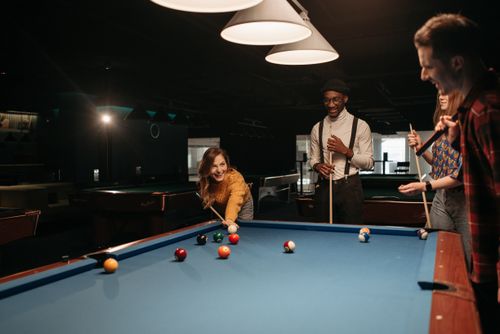 Free Friends having fun playing billiards in a cozy indoor environment. Stock Photo