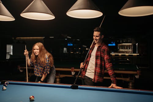 Man and Woman Standing Beside Pool Table