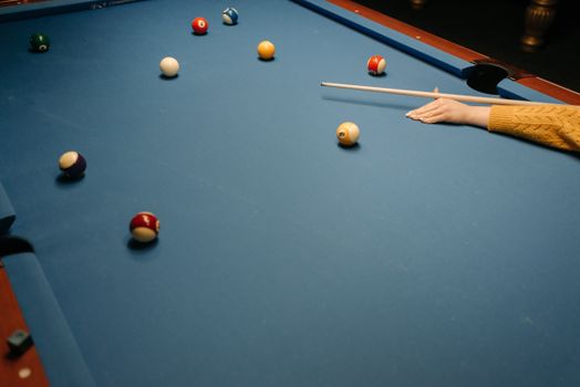 Close-up view of a pool game in action on a blue billiard table, showcasing colorful balls and a cue stick.