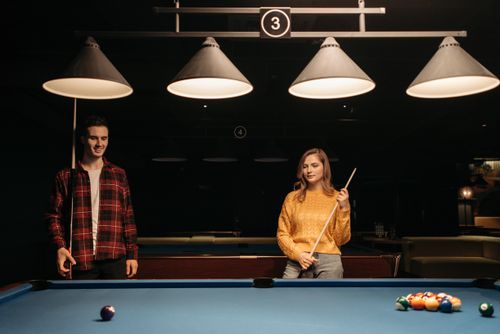 Free A man and woman playing billiards, focusing on a fun leisure activity indoors. Stock Photo