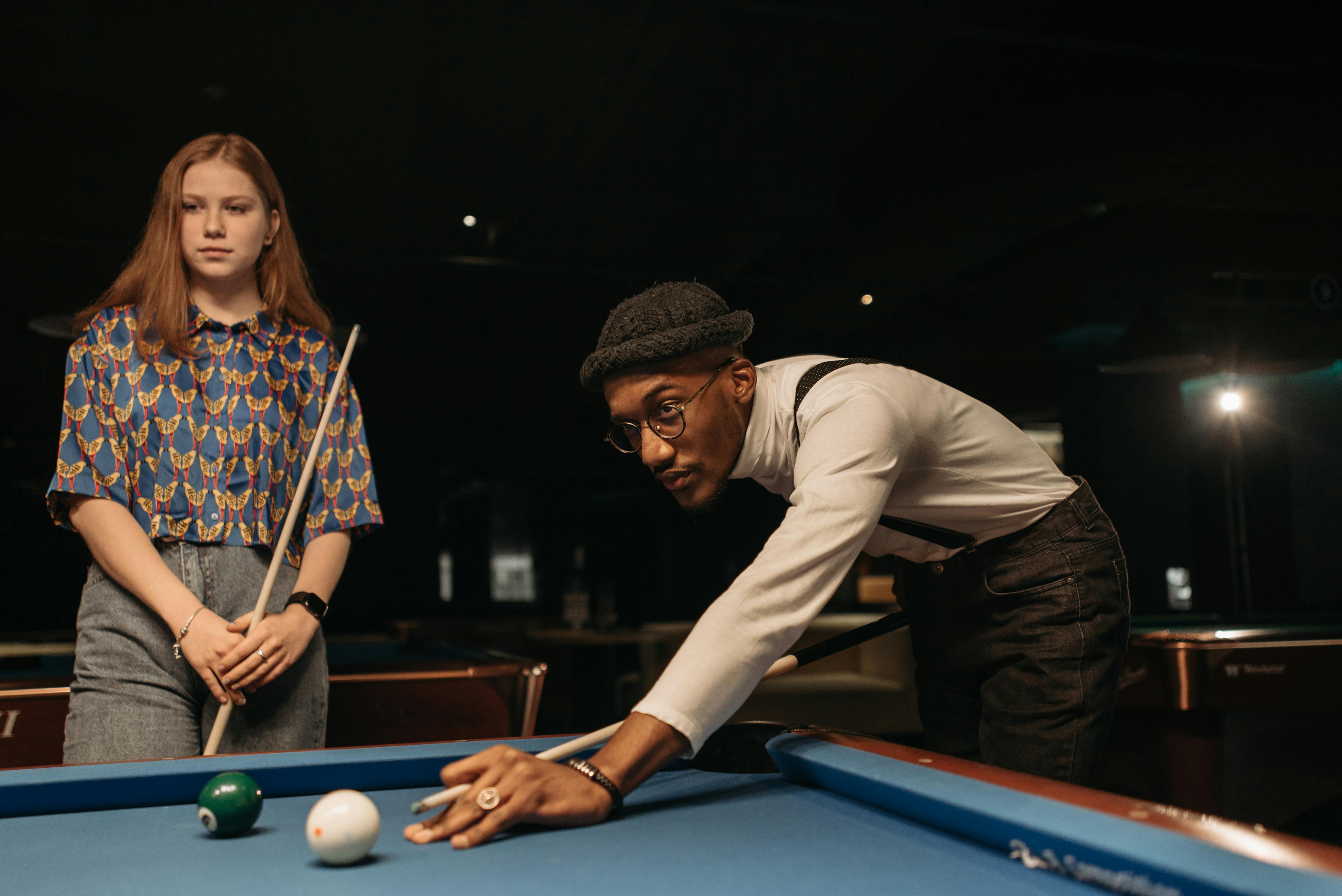 man in white long sleeve shirt and brown knit cap playing billiard