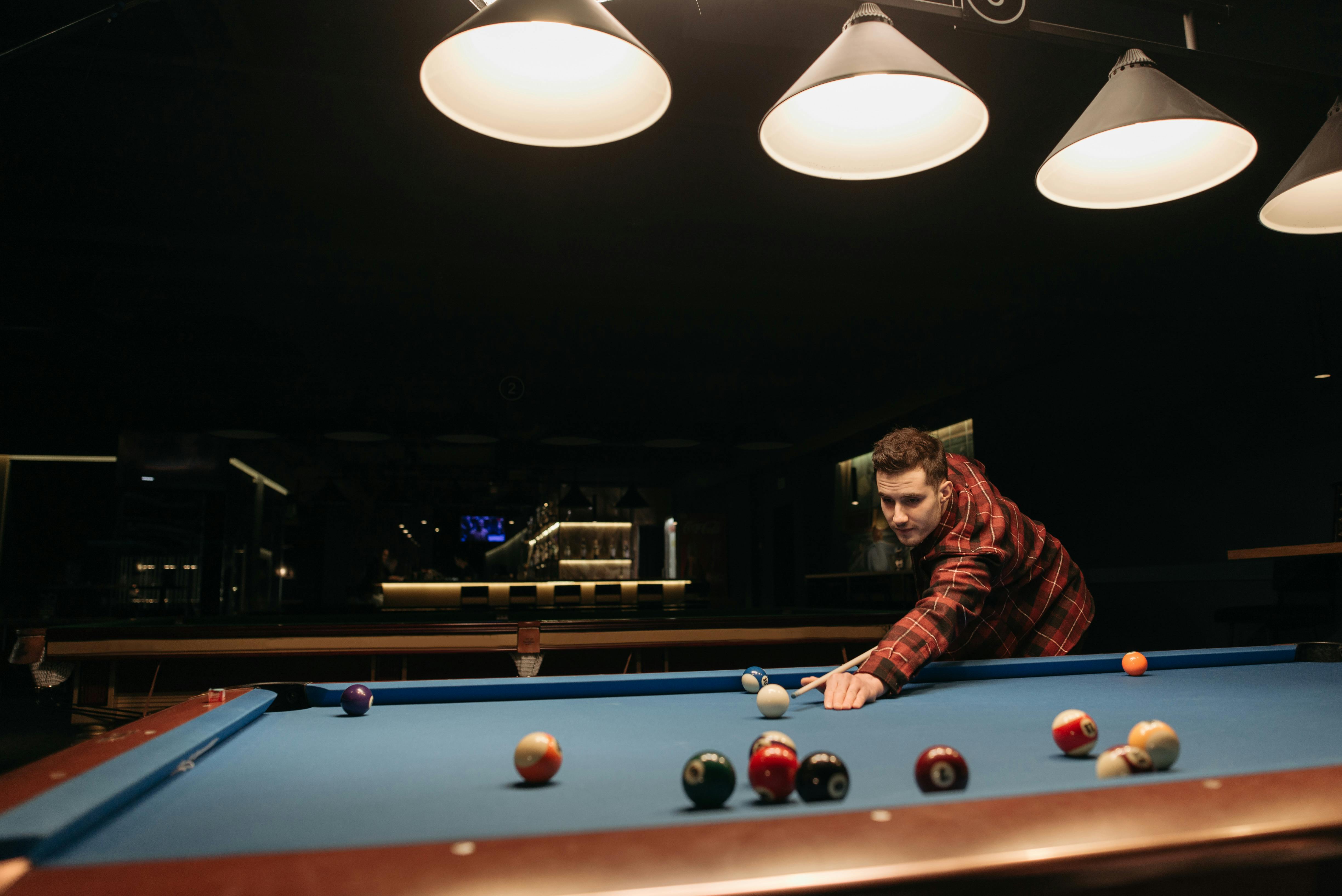 man in red and black plaid shirt playing billiard