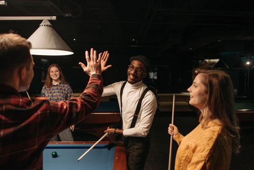 Free Group of diverse friends having fun playing billiards indoors. Stock Photo