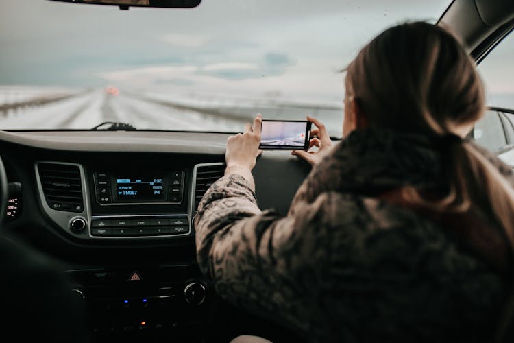 Back View Of A Woman Inside A Car Taking Picture 