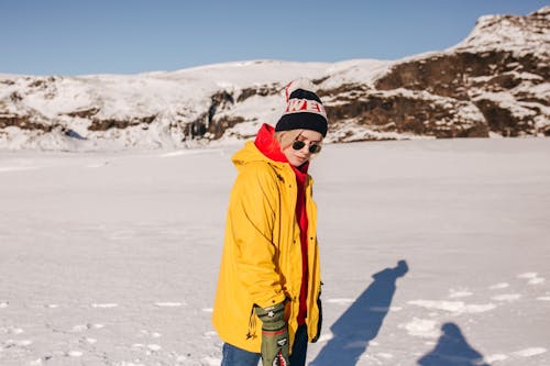 Woman in Yellow Jacket Standing on Snow Covered Ground