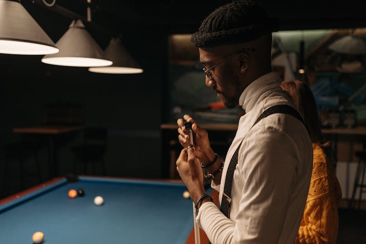 A Man Putting Chalk On A Cue Stick