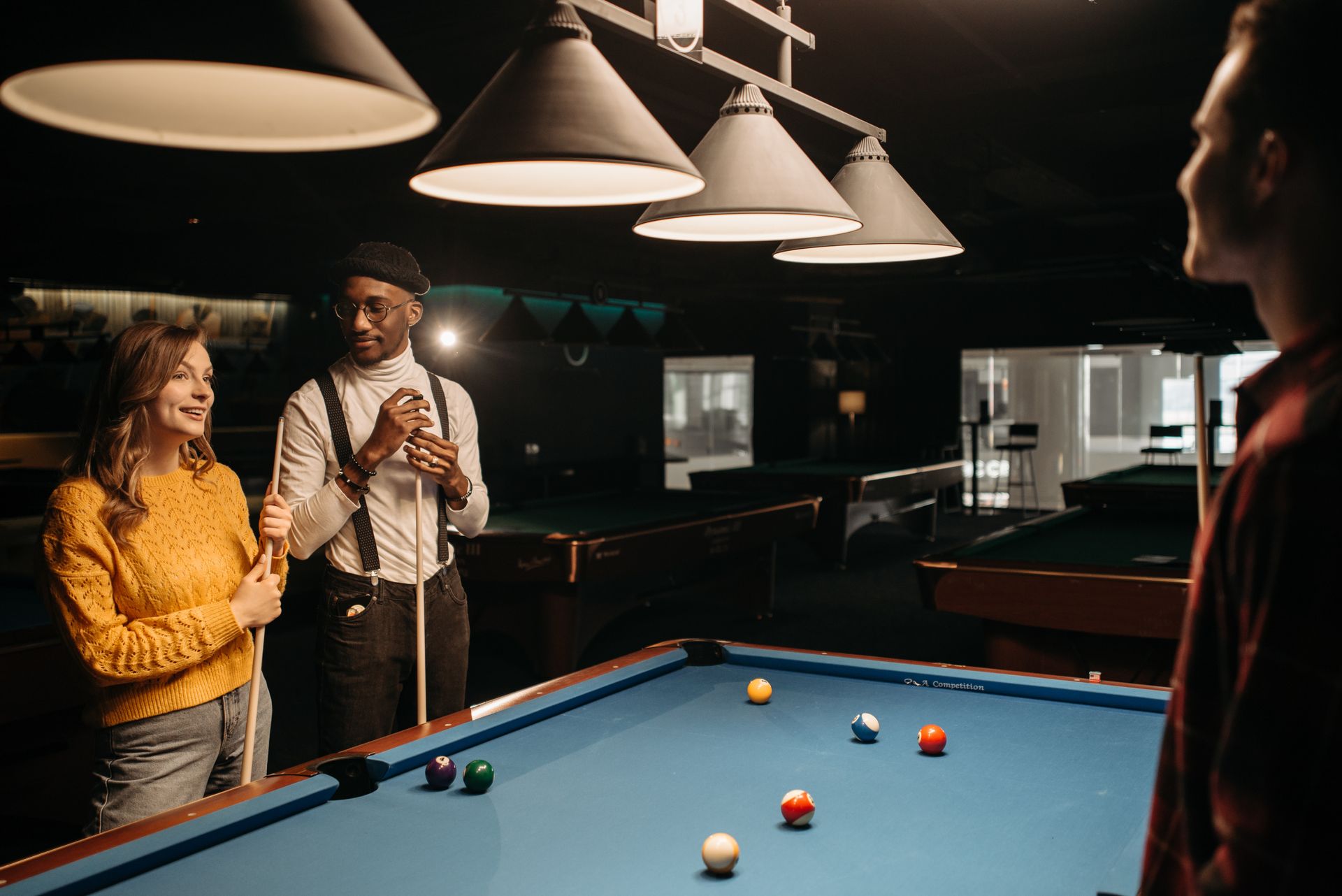 Group of young friends hanging out and playing billiards indoors.
