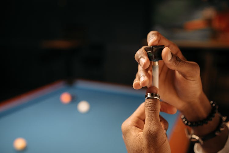 A Person Putting Chalk On A Cue Stick