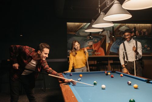 Free Group of friends having fun playing billiards in a cozy indoor setting. Stock Photo