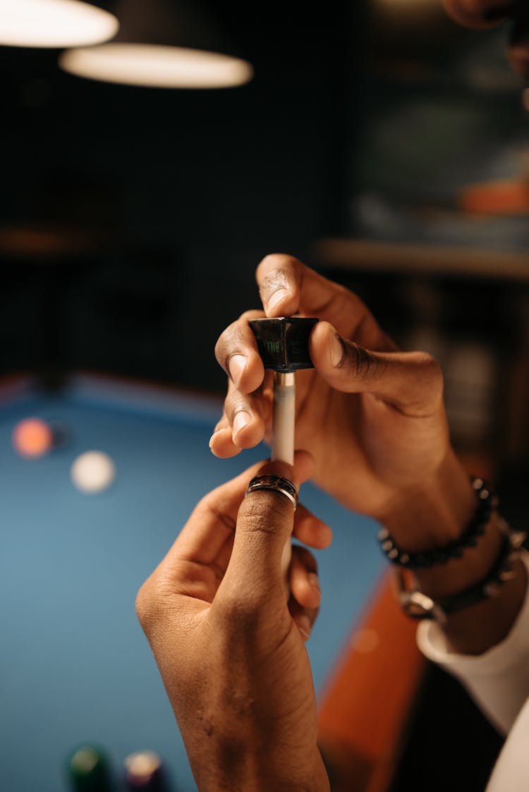 A Person Putting Chalk On A Cue Stick