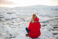 A Woman in Red Hoodie Sitting on Snow Covered Ground