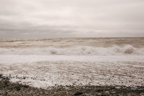 Free Tranquil scene of waves crashing on the shore under a cloudy sky. Stock Photo