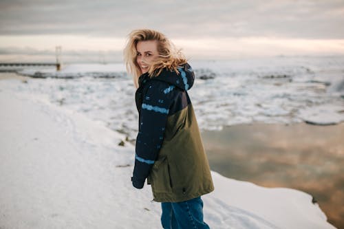 Woman Wearing Winter Jacket while Walking on Snow Field