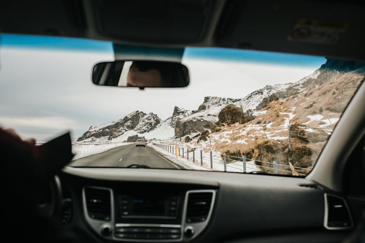 Person Driving A Car On The Road Near Mountains