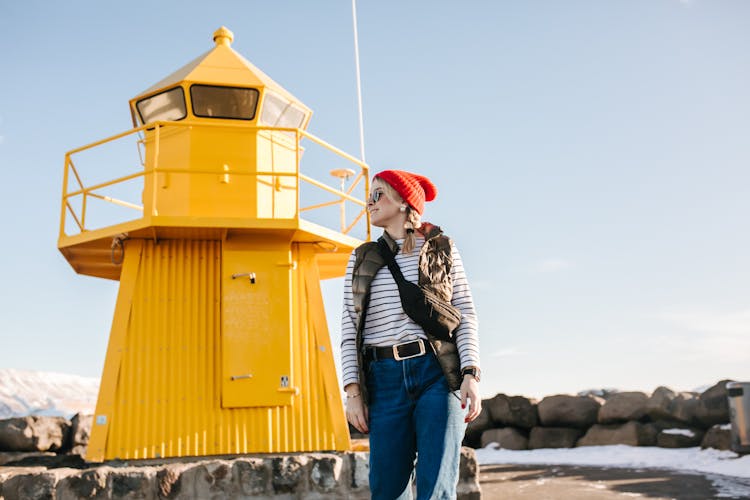 Woman Standing Beside A Yellow Lighthouse