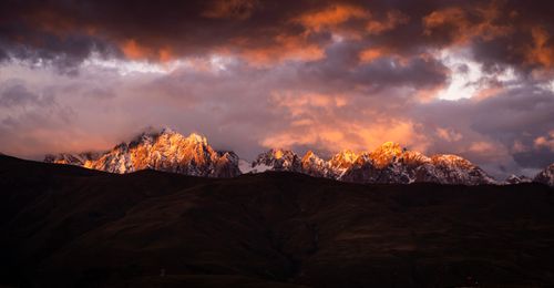 Free Stunning view of snow-capped mountains illuminated by a dramatic sunset sky. Stock Photo