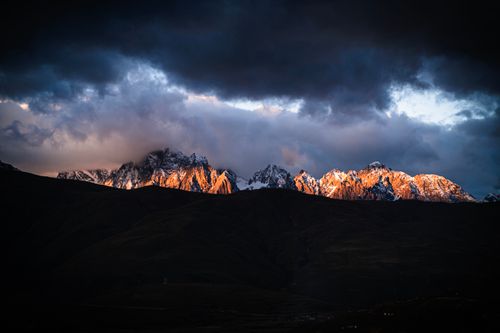 Free Stunning view of a sunset highlighting snow-capped mountains under a dramatic sky. Stock Photo