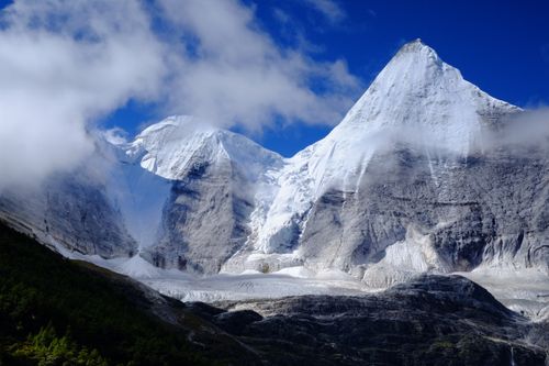 Free Capture of a snow-covered mountain peak under a clear blue sky with fluffy clouds. Stock Photo