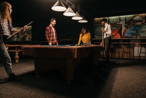 Free People playing pool indoors, enjoying a recreational activity with friends. Stock Photo