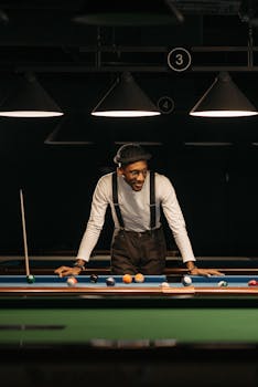 A stylish man in suspenders playing pool in a dimly lit billiard hall.