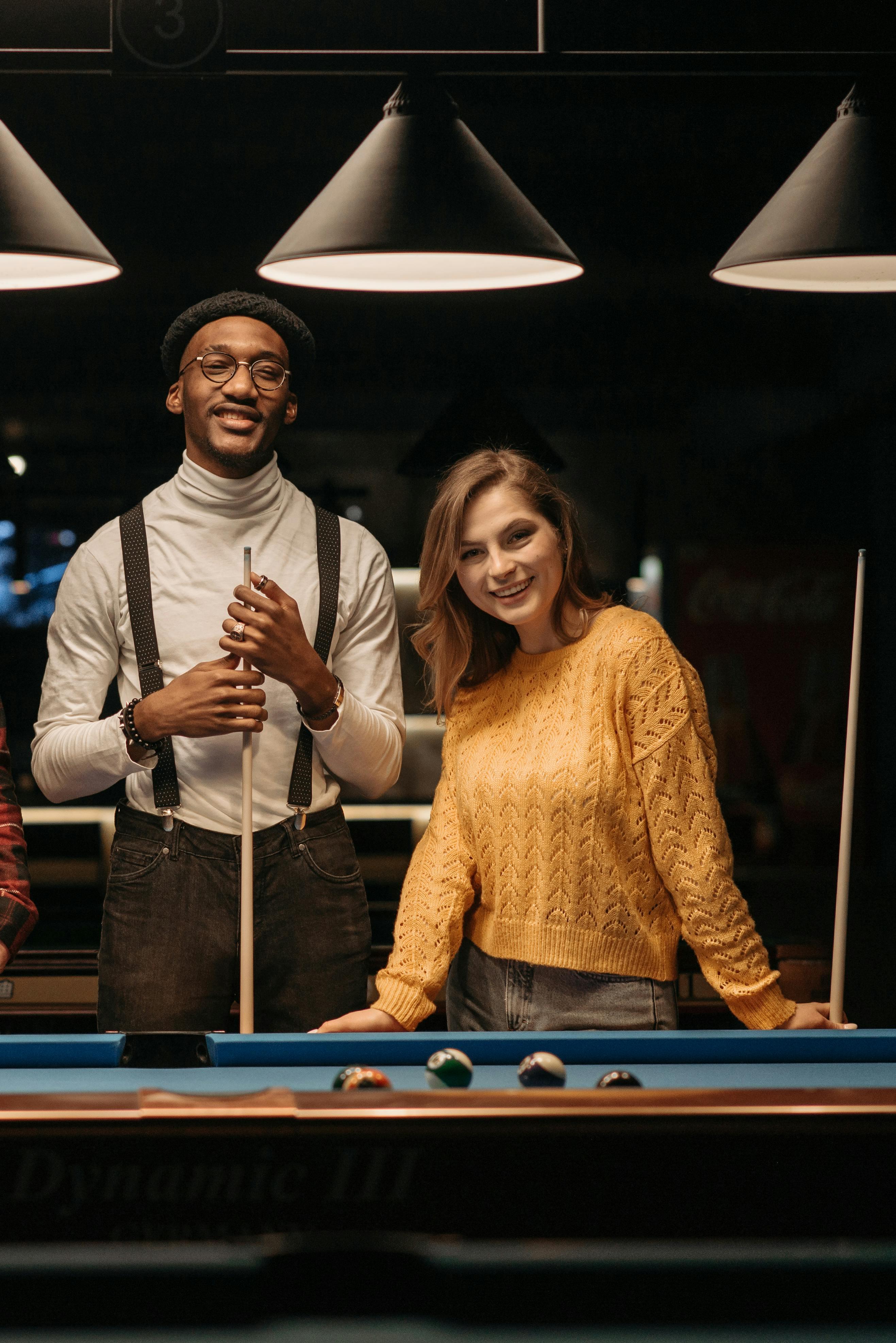 man and woman standing beside a billiard table